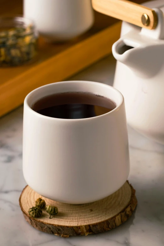 the cup of black coffee is sitting on a wood board