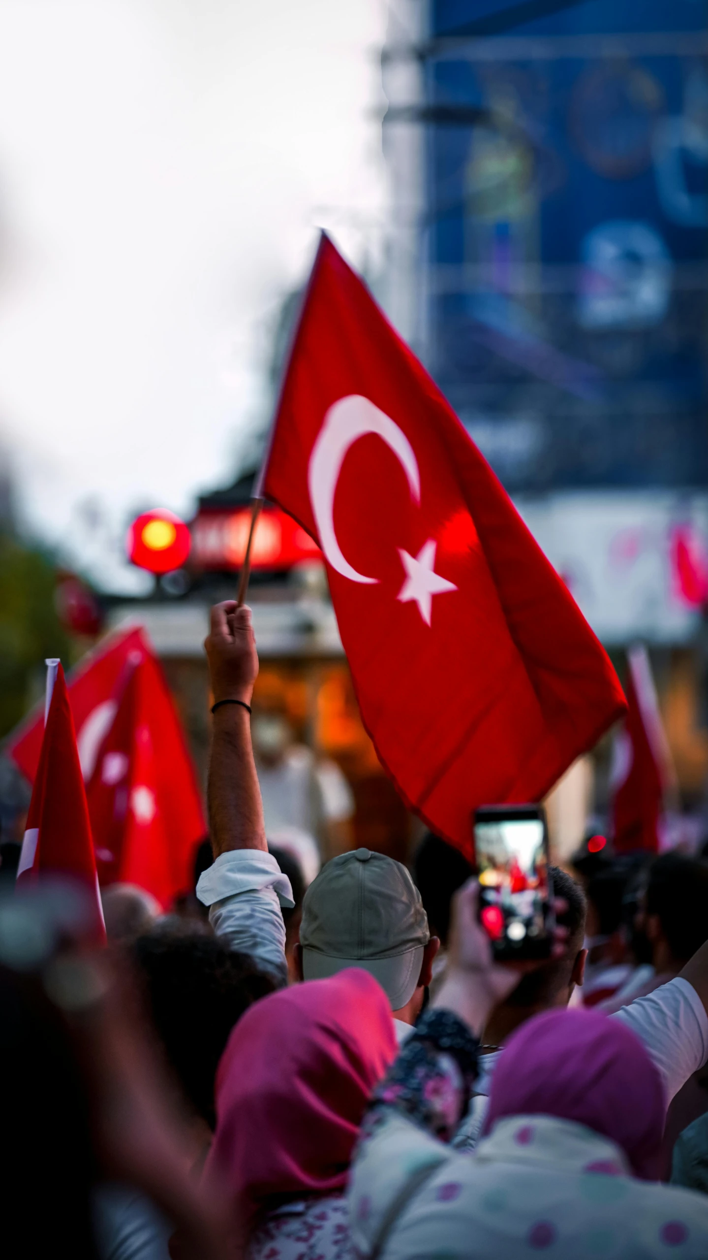 people in the crowd holding turkish flags and a cell phone