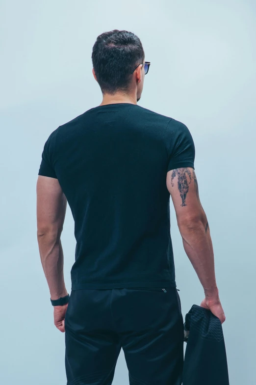 a man standing next to the sea while holding onto a black bag