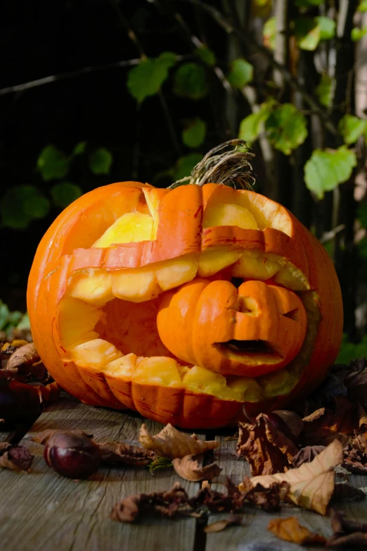 a carved pumpkin in the leaves is laying on a wooden floor