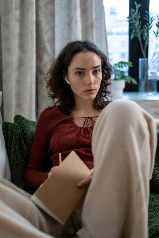 a woman sitting on top of a couch next to curtains