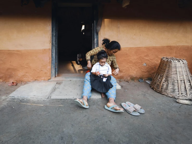 the woman holds a baby near her feet