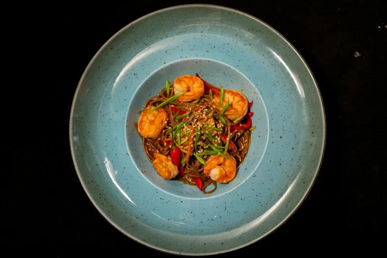 a blue bowl containing shrimp and a stir fry