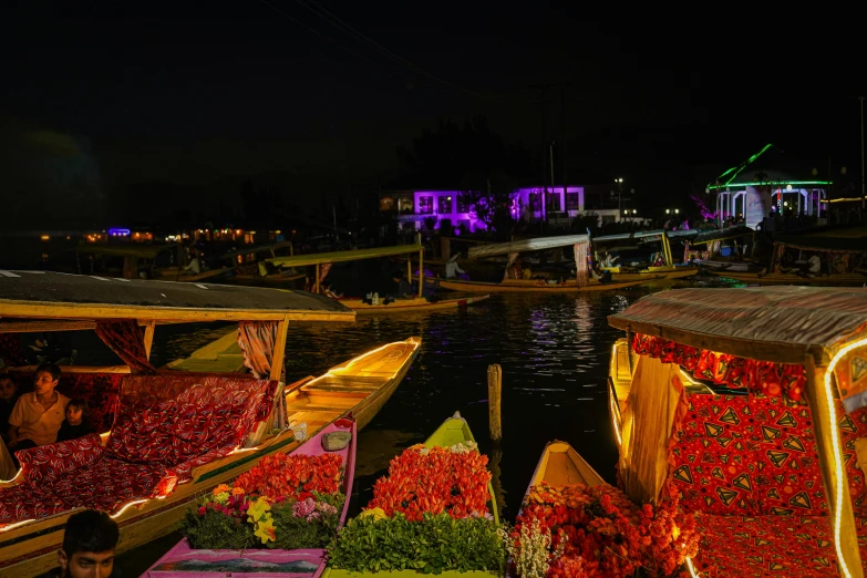 a boat is filled with colorful flowers by the shore