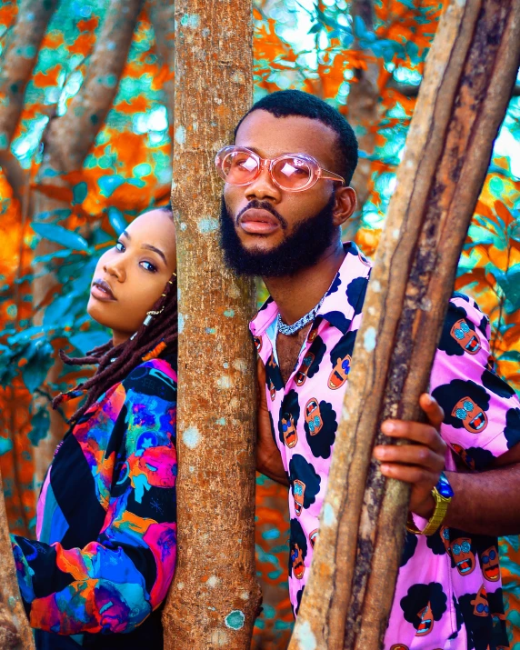 a man and a woman in sunglasses hugging behind trees