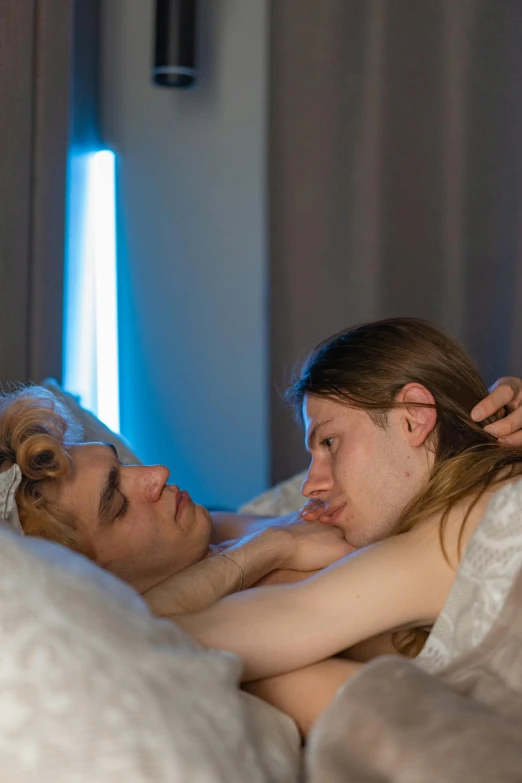 a woman laying in bed with another person holding her head