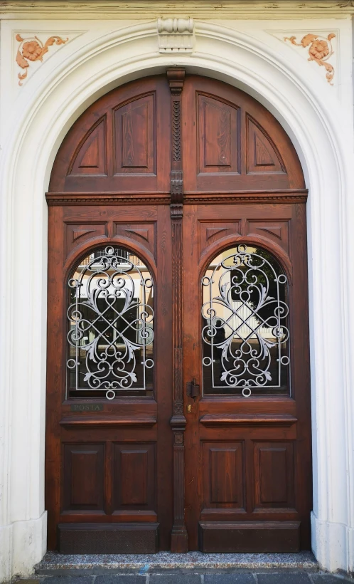 a two wooden doors that have decorative glass panels on them