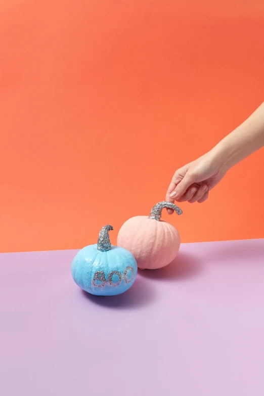a hand is grabbing soing off the tip of a small pumpkin