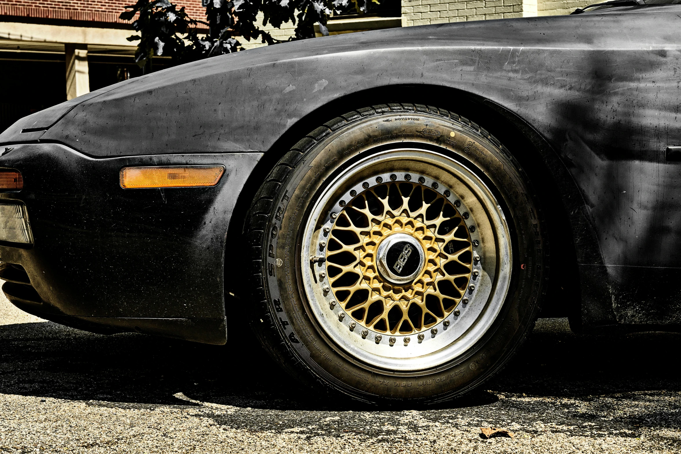 a black sports car with gold spokes is parked