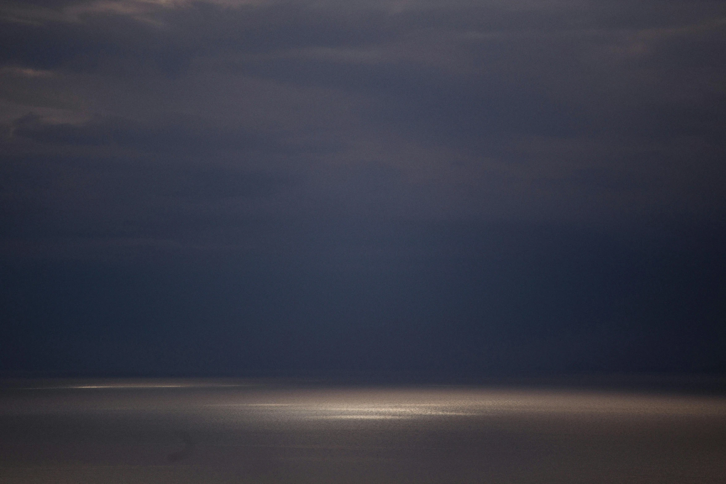 an ocean landscape with a small boat and the moon behind