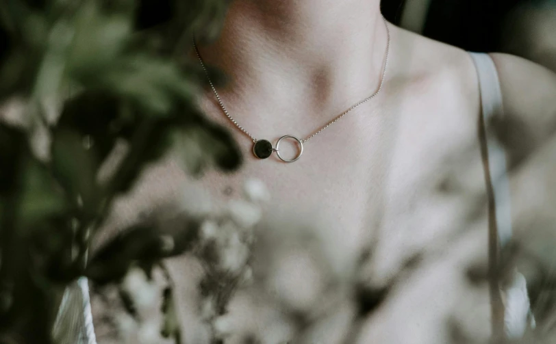 the woman is wearing a necklace with an oval shape