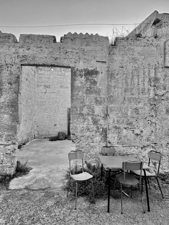 an old wall that has a table and chairs outside