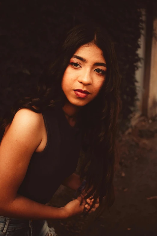 a  with long hair standing in front of a brick wall