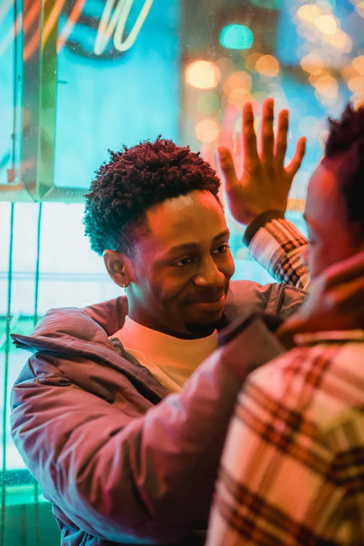 a man smiling at his friend standing behind him with their hands in the air