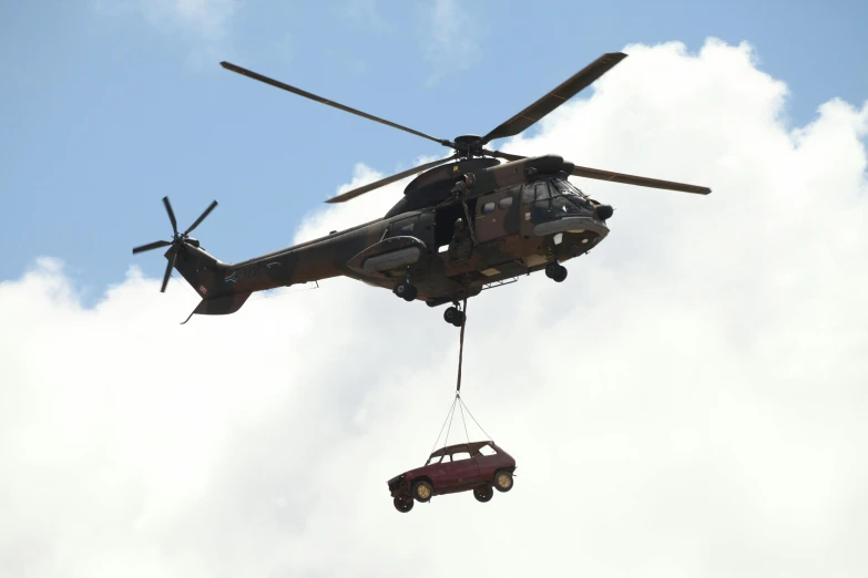 a truck being lifted from a helicopter by tow ropes