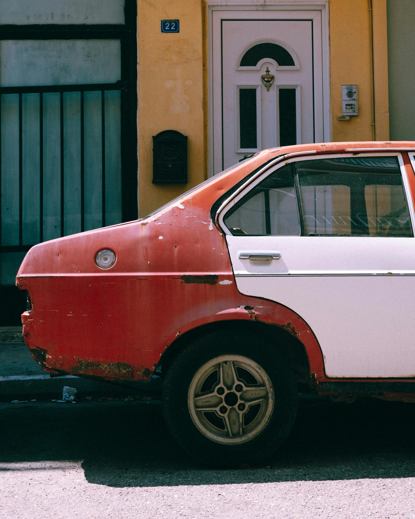 an old red and white compact parked on the street