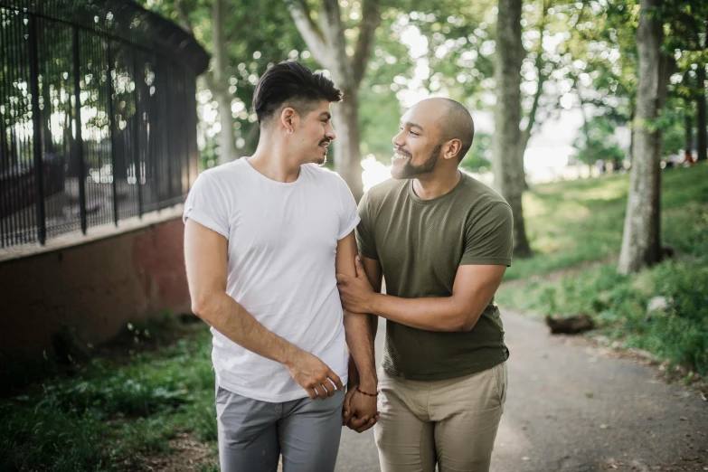 a young couple smiling in front of a bridge and trees