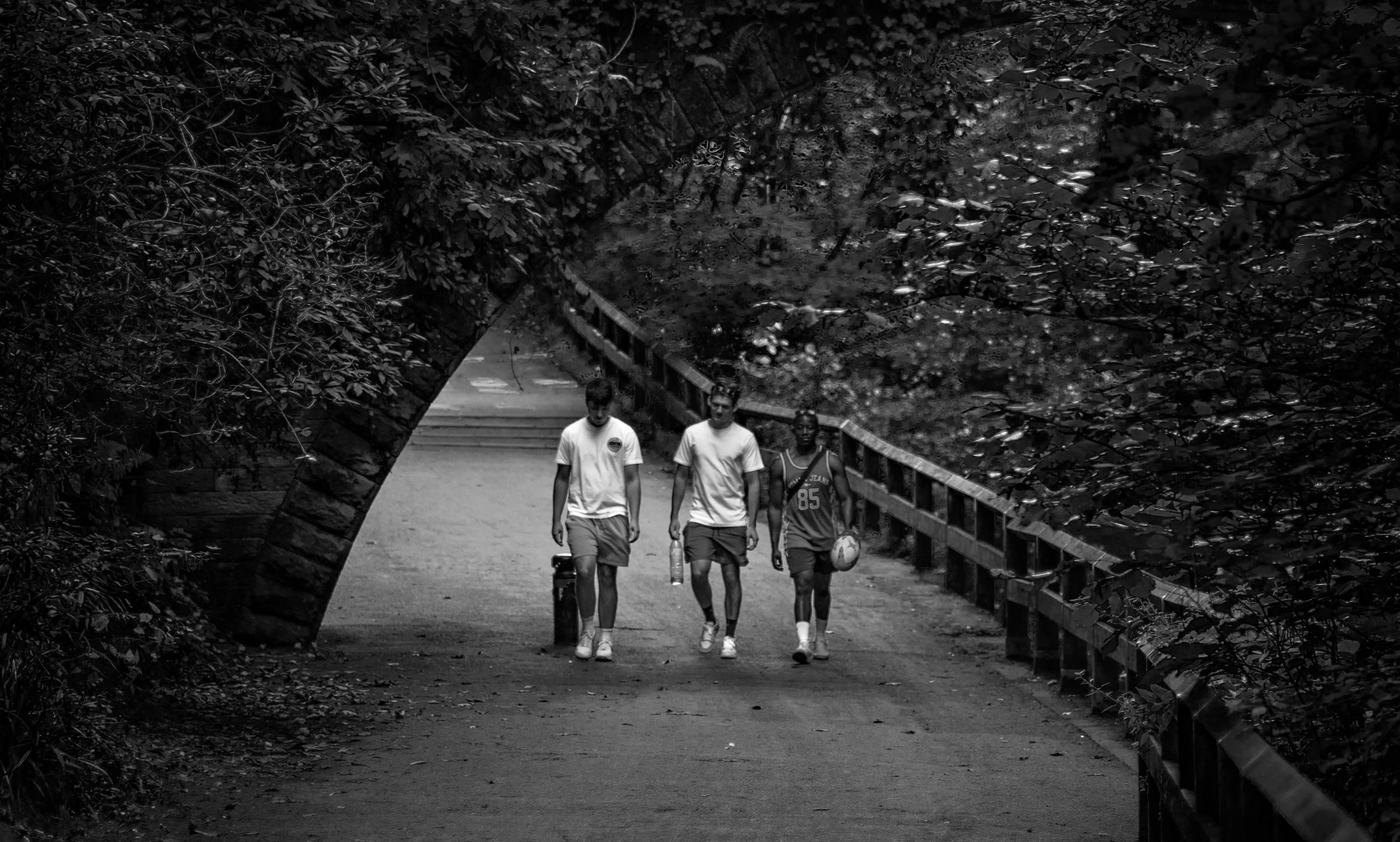 two boys walking on a pathway holding umbrellas