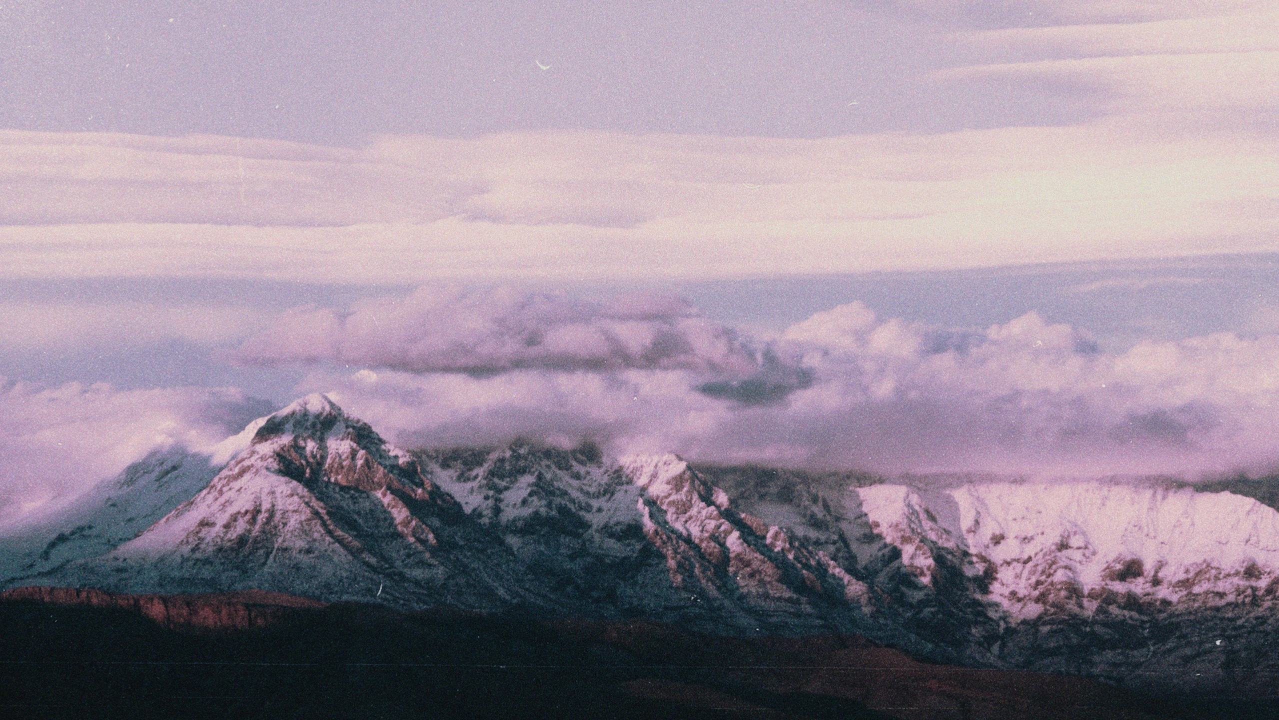 snow covered mountains stand in the foreground and appear to be covered by cloudy sky