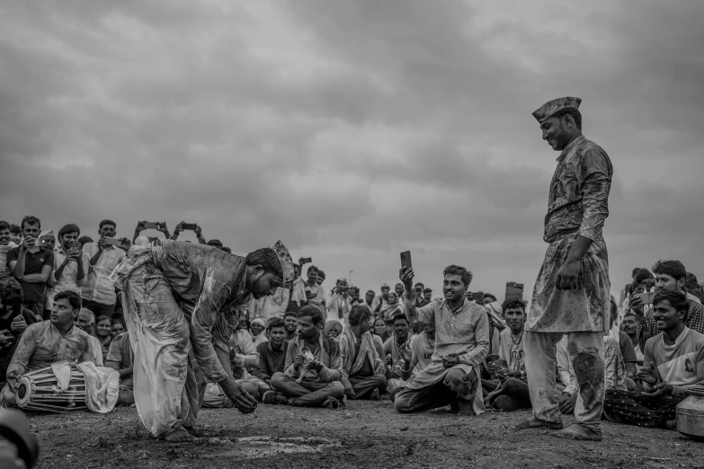 men sitting and standing around a crowd under a cloudy sky