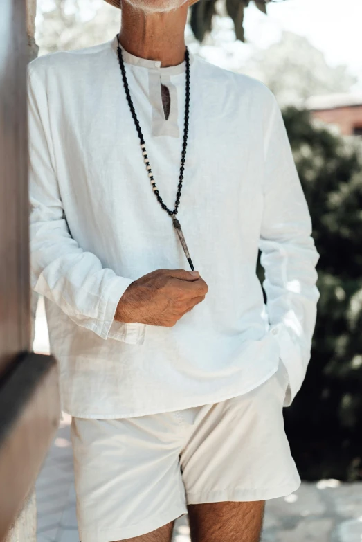 a man wearing a necklace and wearing white