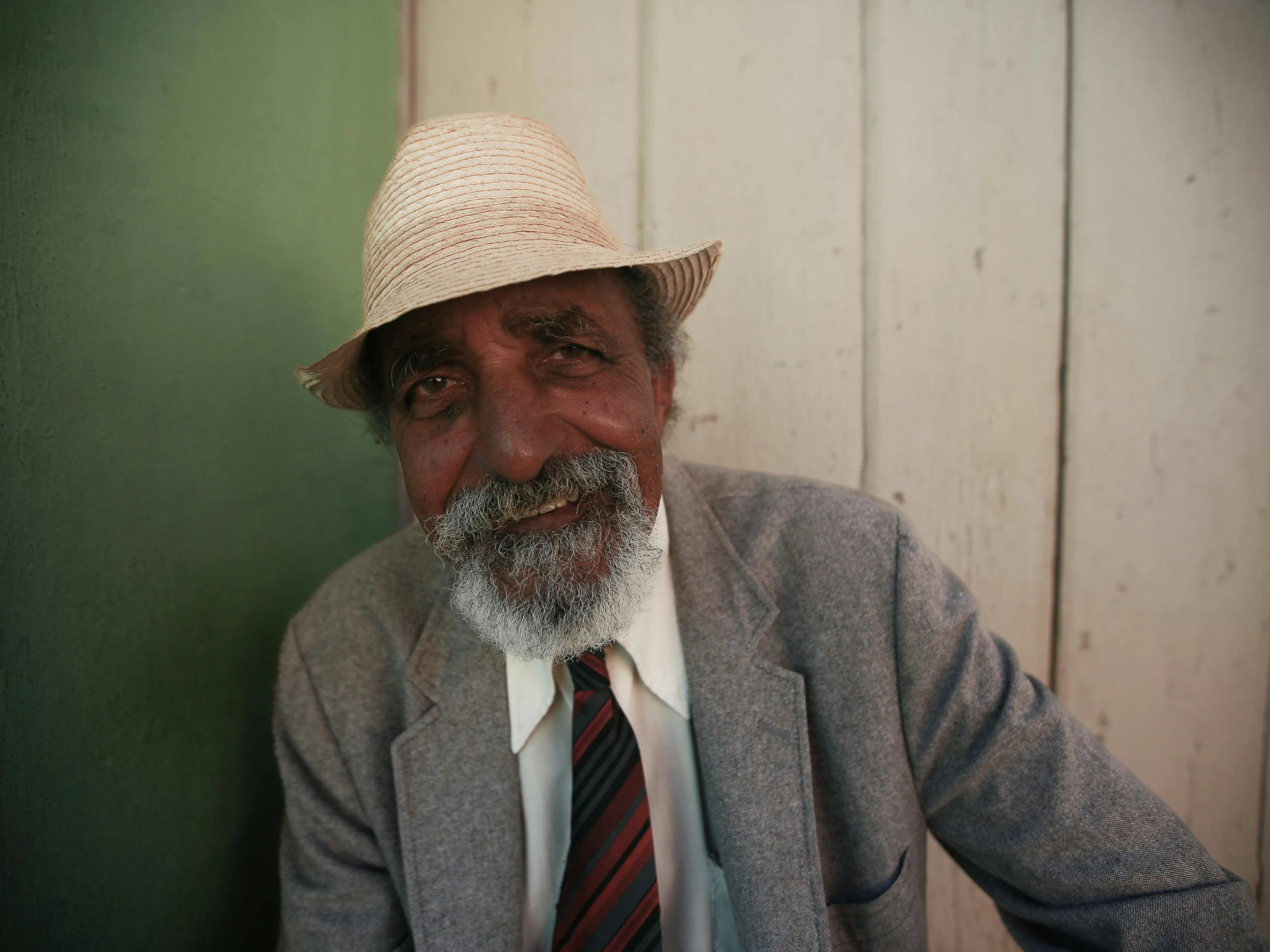 an old man is wearing a hat and tie