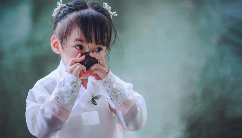 a  dressed in a white chinese clothing holding soing over her mouth