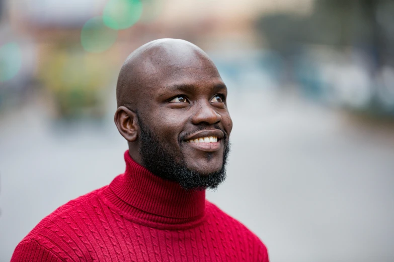 a bald headed black man wearing a red turtle neck