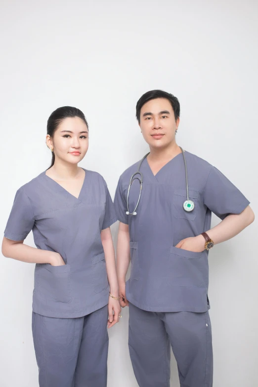an asian woman in a grey scrubs standing next to a male in blue scrubs