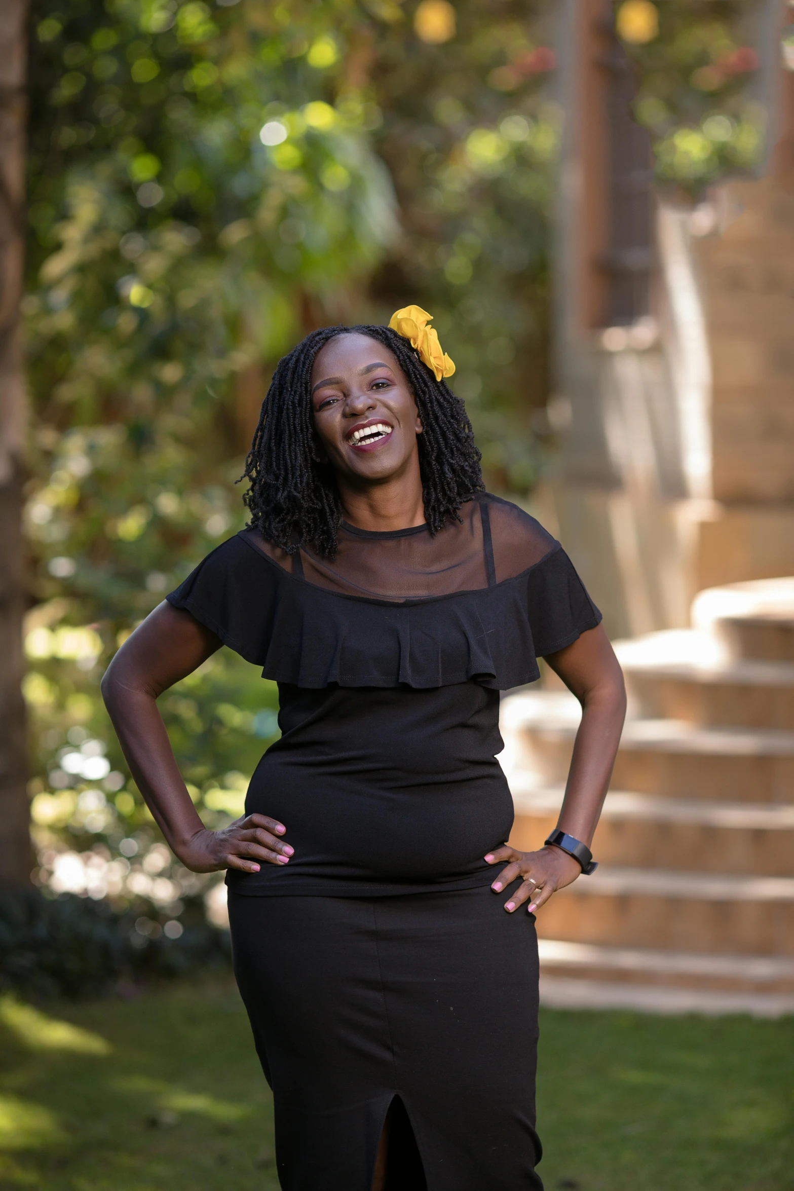 a woman poses in front of steps and trees