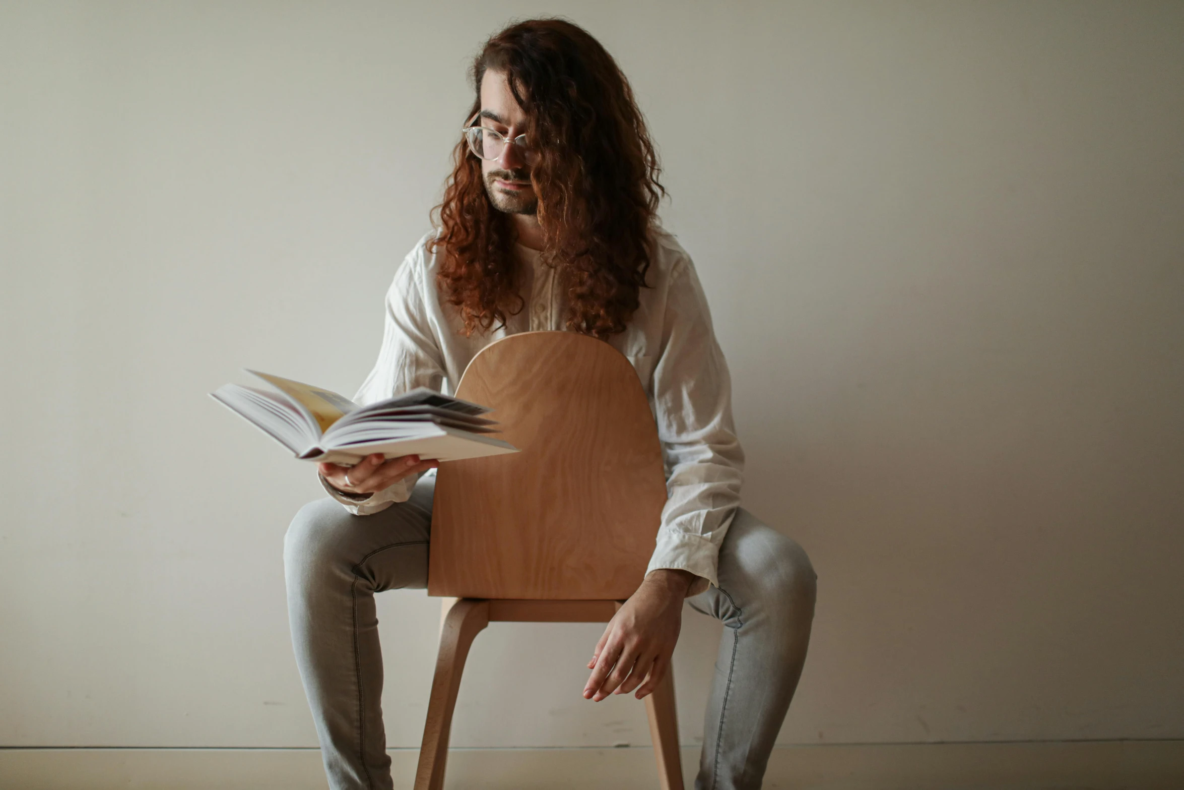 a woman sitting on a chair and reading a book