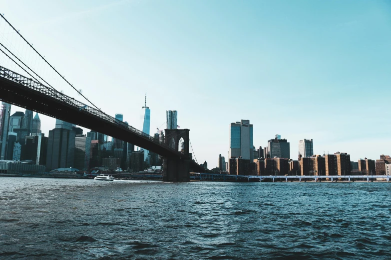 a boat passing under the bridge and a big city in the background