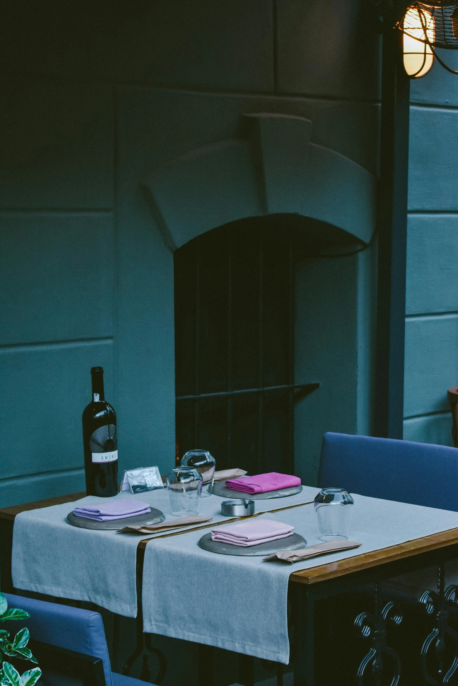 a table with two place settings, wine bottle and candle on it