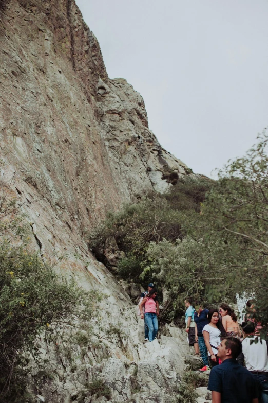 group of people walking up a mountain with rocky mountains in the background