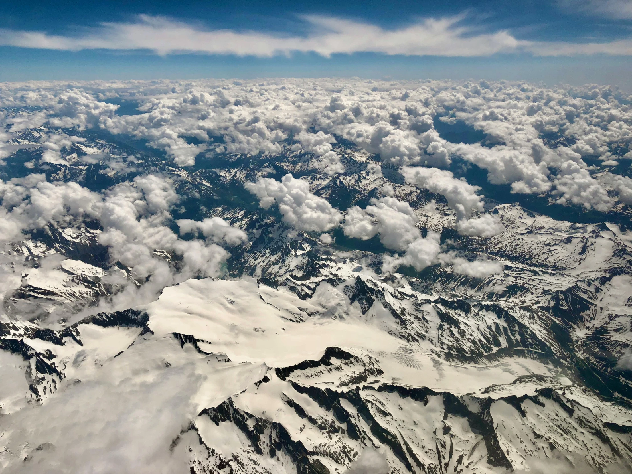 view from the window of an airplane looking at snow capped mountains and valleys