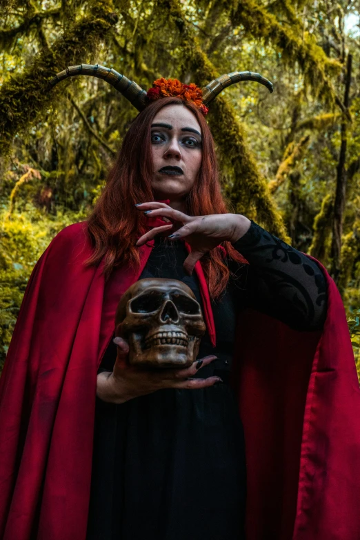 the red - haired girl with a horns and devil makeup stands next to a creepy skull