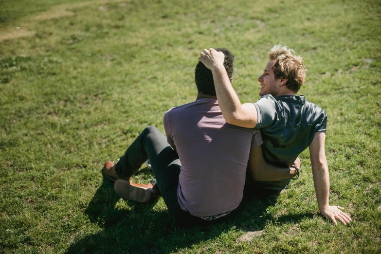 a man holding onto another mans back on top of the grass