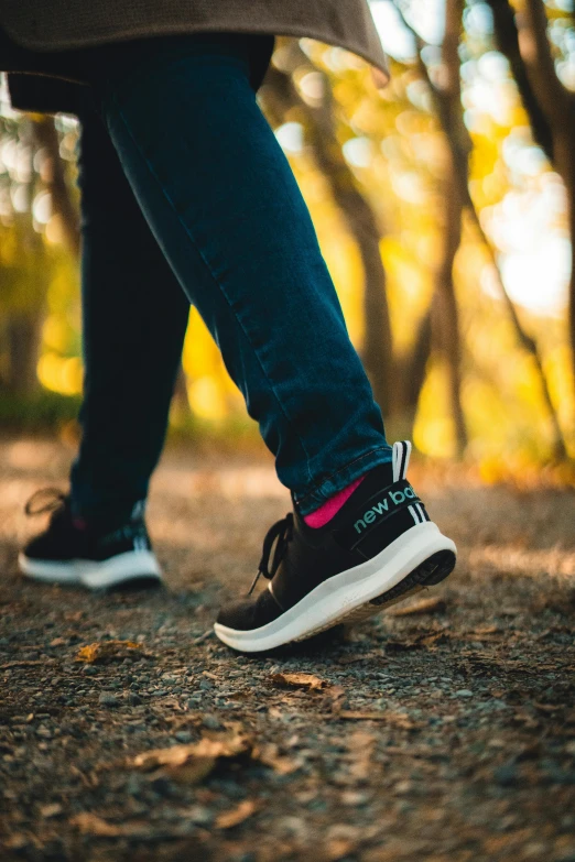 the feet of a person wearing tennis shoes in a wooded area