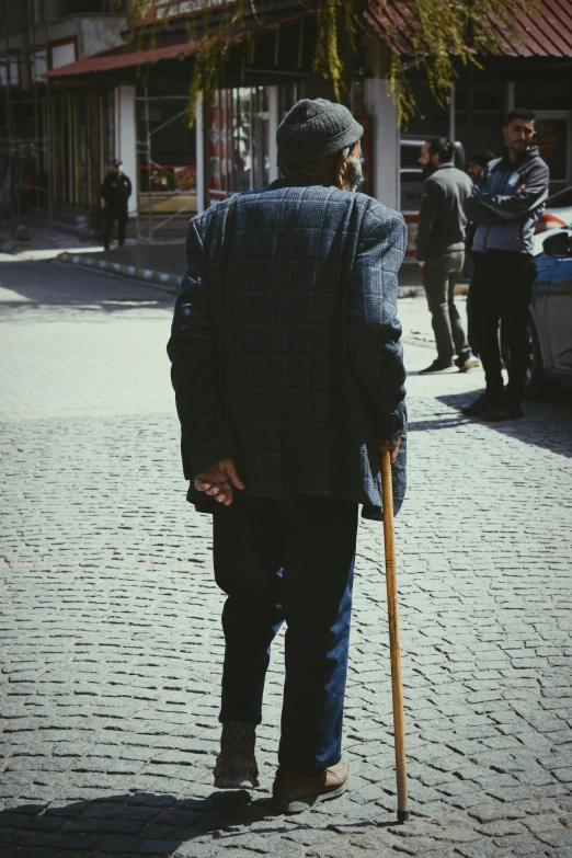 an elderly man walking while holding a cane