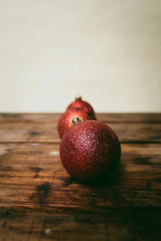 two red apple laying on top of a wooden table