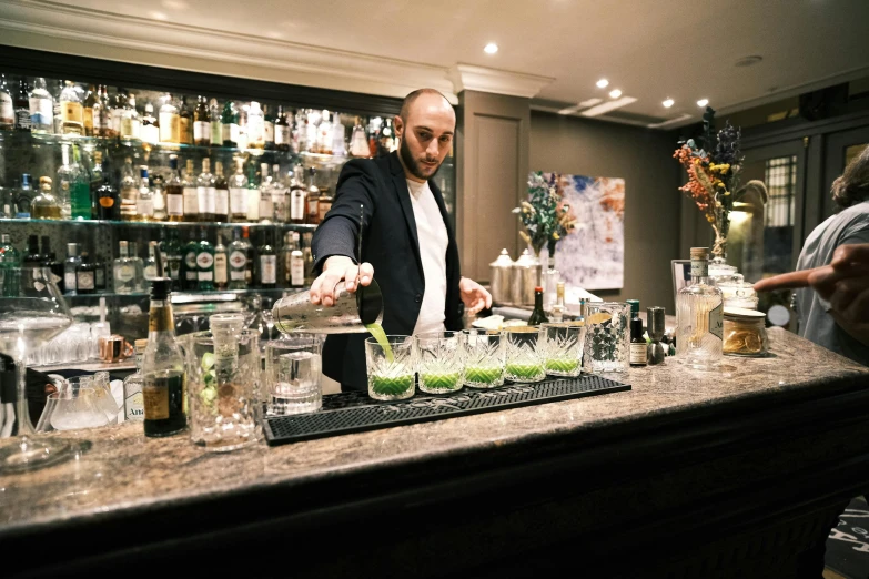 a man stands at a bar preparing some drinks