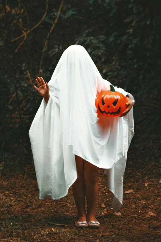 a woman in a white dress and hat holding a plastic pumpkin bag