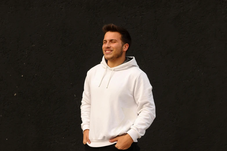 a smiling man in white standing with his arms crossed