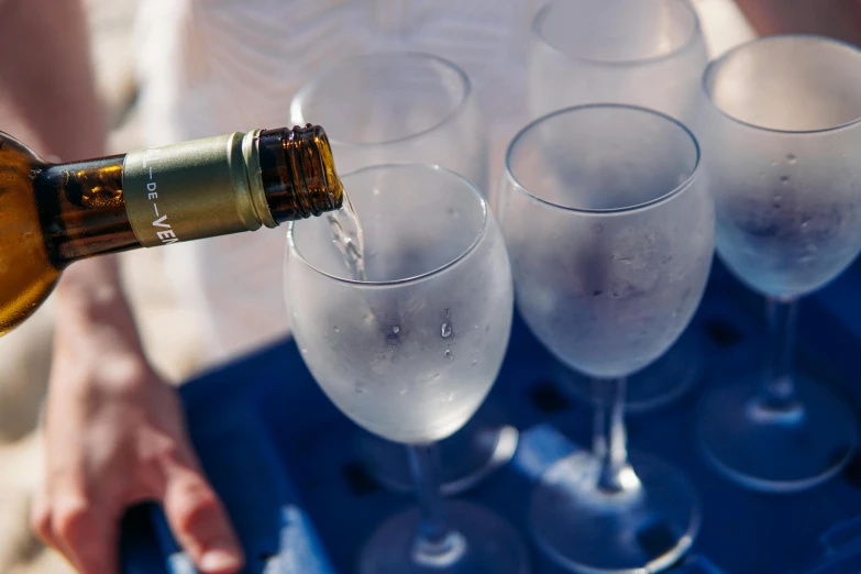 a person pouring champagne into a glass filled with white liquid