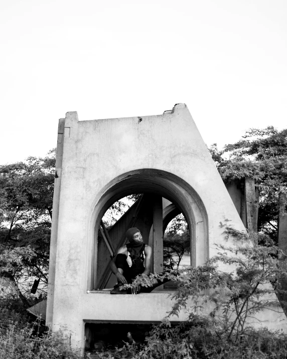 a black and white image of a woman looking out of an arch