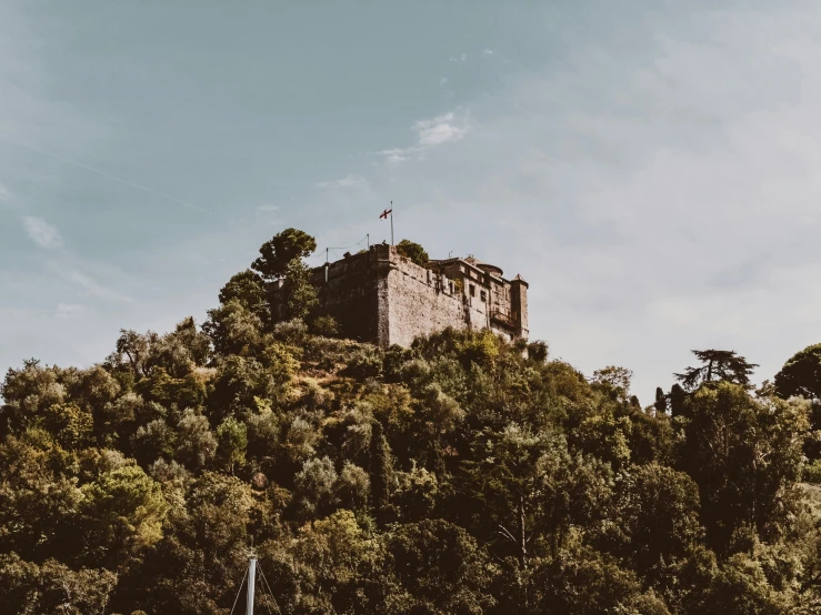 an old castle stands atop the trees on a hillside