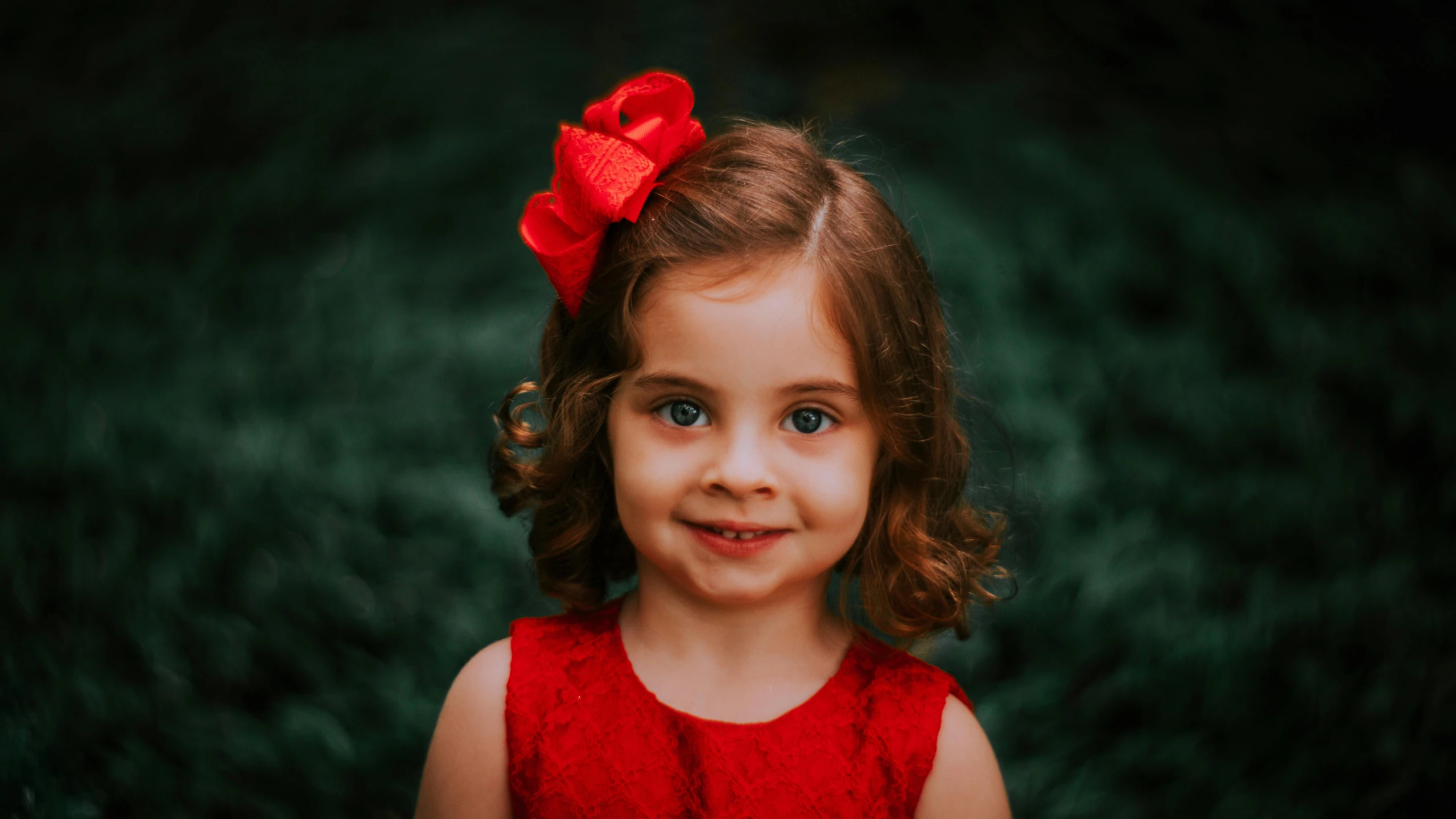 little girl with big hair smiling in the grass