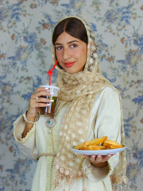 a woman is wearing a shawl and holding a plate of food