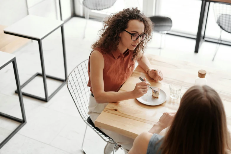 a woman at a table in an empty restaurant with a plate and fork in front of her