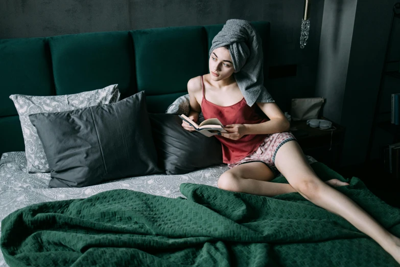 a woman sitting on a bed reading a book